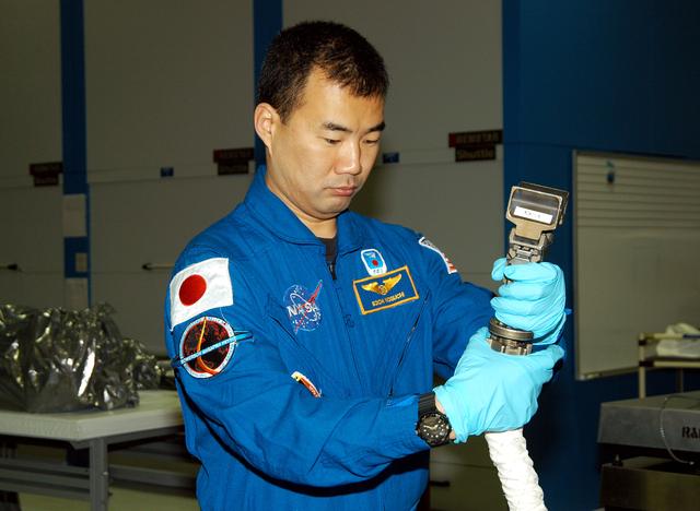 NASA image: KENNEDY SPACE CENTER, FLA. -  STS-114 Mission Specialist Soichi Noguchi, with the Japanese Aerospace Exploration Agency (JAXA), handles equipment that will be used on the mission.  He and other crew members are at KSC for equipment familiarization.  STS-114 is classified as Logistics Flight 1 to the International Space Station,  delivering new supplies and replacing one of the orbital outpost’s Control Moment Gyroscopes (CMGs). STS-114 will also carry a Raffaello Multi-Purpose Logistics Module and the External Stowage Platform-2.  The crew is slated to conduct at least three spacewalks: They will demonstrate repair techniques of the Shuttle’s Thermal Protection System,  replace the failed CMG with one delivered by the Shuttle, and  install the External Stowage Platform.