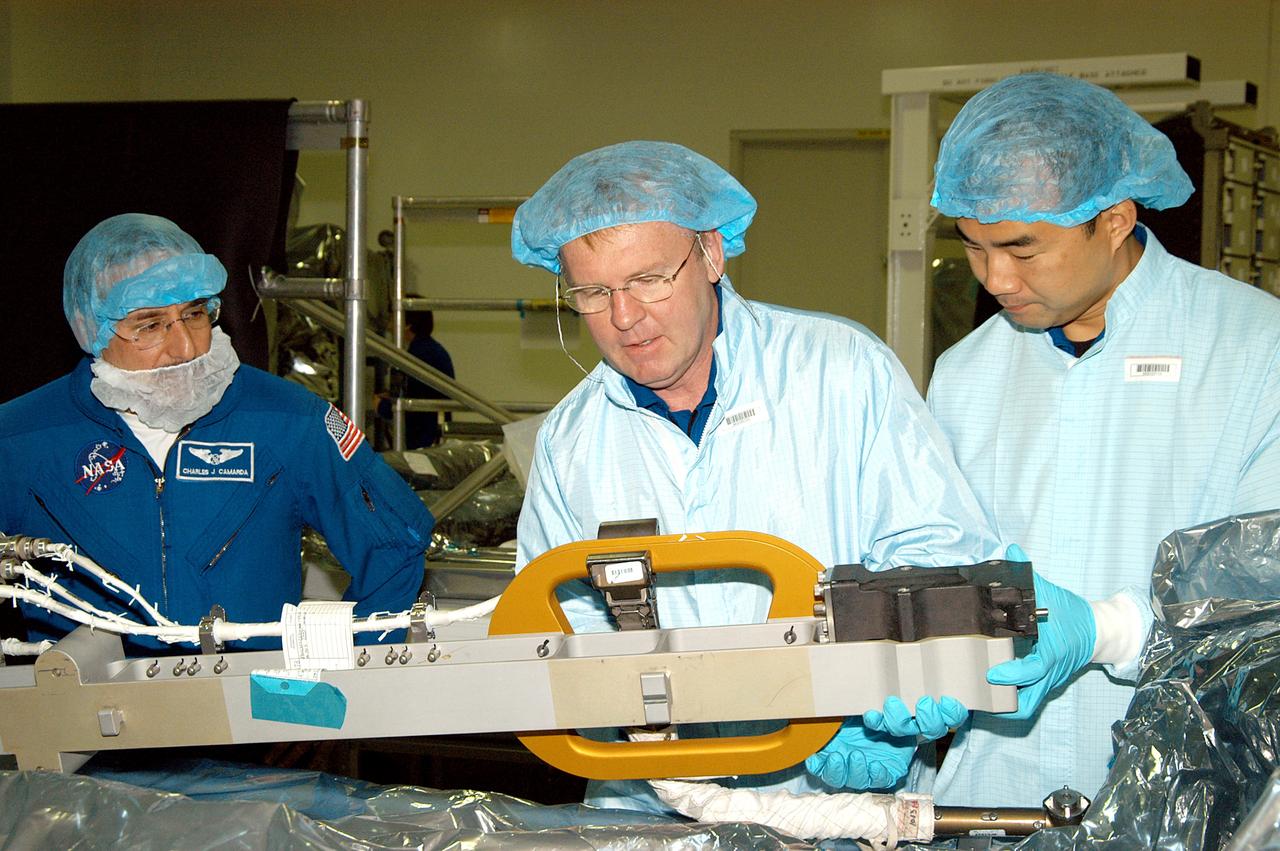 KENNEDY SPACE CENTER, FLA. -  In the Space Station Processing Facility, STS-114 Mission Specialists Andrew Thomas (center) and Soichi Noguchi (right) work with equipment while Mission Specialist Charles Camarda (left) watches.  Noguchi is with the Japanese Aerospace Exploration Agency (JAXA).  They and other crew members are at KSC for equipment familiarization.  STS-114 is classified as Logistics Flight 1 to the International Space Station, delivering new supplies and replacing one of the orbital outpost’s Control Moment Gyroscopes (CMGs). STS-114 will also carry a Raffaello Multi-Purpose Logistics Module and the External Stowage Platform-2.  The crew is slated to conduct at least three spacewalks: They will demonstrate repair techniques of the Shuttle’s Thermal Protection System,  replace the failed CMG with one delivered by the Shuttle, and  install the External Stowage Platform.