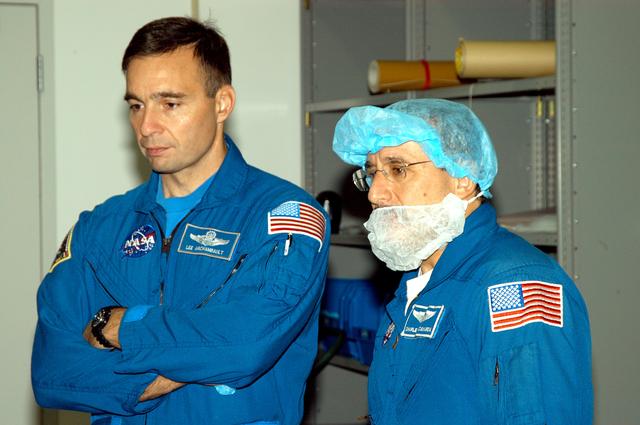 KENNEDY SPACE CENTER, FLA. -  In the Space Station Processing Facility, astronaut Lee Archambault and STS-114 Mission Specialist Charles Camarda watch as crew members work with equipment that will be used on the mission.  Archambault supports launch and landing operations at the Kennedy Space Center as an Astronaut Office representative. Crew members are at KSC for equipment familiarization.  STS-114 is classified as Logistics Flight 1 to the International Space Station, delivering new supplies and replacing one of the orbital outpost’s Control Moment Gyroscopes (CMGs). STS-114 will also carry a Raffaello Multi-Purpose Logistics Module and the External Stowage Platform-2.  The crew is slated to conduct at least three spacewalks: They will demonstrate repair techniques of the Shuttle’s Thermal Protection System,  replace the failed CMG with one delivered by the Shuttle, and  install the External Stowage Platform.
