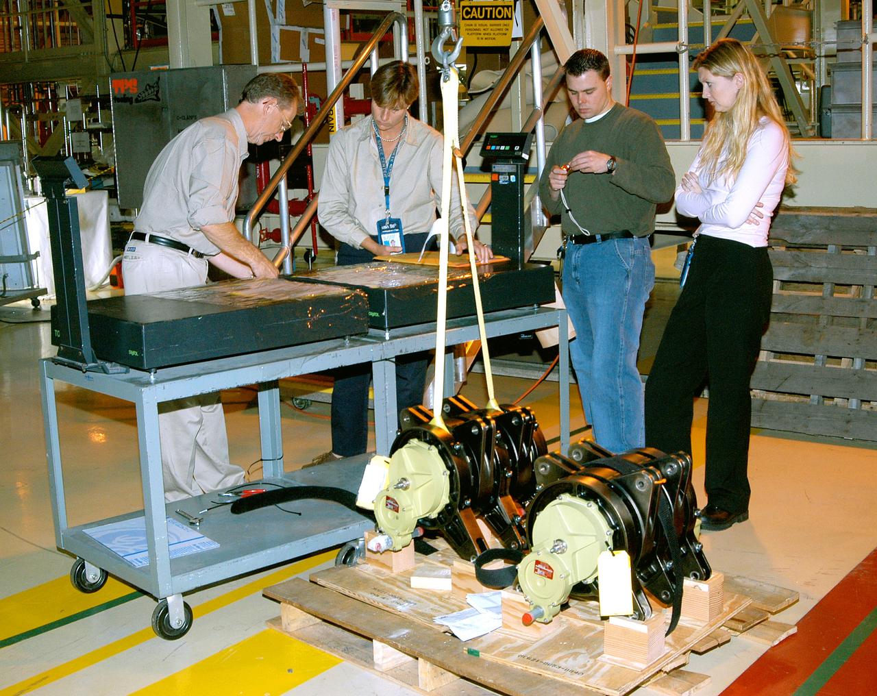 KENNEDY SPACE CENTER, FLA. -  Workers in the Orbiter Processing Facility get ready to measure the alignment of the bearings on the rudder speed brake actuators sitting on the floor in the foreground.  The actuators move an orbiter’s rudder, speed brake, elevons and main engines during flight.