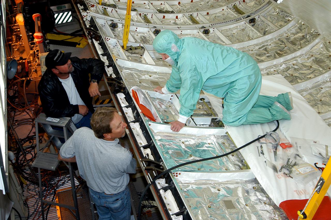 KENNEDY SPACE CENTER, FLA. -  A worker in the Orbiter Processing Facility checks part of the payload bay on Discovery.  The orbiter recently underwent an Orbiter Major Modification period, which included inspection, modifications and reservicing of most systems onboard. The work on Discovery also included the installation of a Multifunction Electronic Display Subsystem (MEDS) - a state-of-the-art “glass cockpit.”  The orbiter is now being prepared for eventual launch on a future mission.