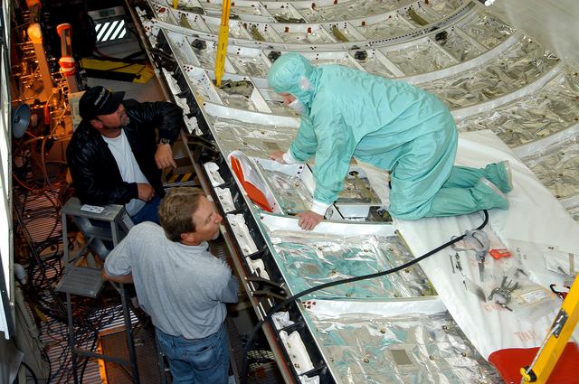 NASA image: KENNEDY SPACE CENTER, FLA. -  A worker in the Orbiter Processing Facility checks part of the payload bay on Discovery.  The orbiter recently underwent an Orbiter Major Modification period, which included inspection, modifications and reservicing of most systems onboard. The work on Discovery also included the installation of a Multifunction Electronic Display Subsystem (MEDS) - a state-of-the-art “glass cockpit.”  The orbiter is now being prepared for eventual launch on a future mission.