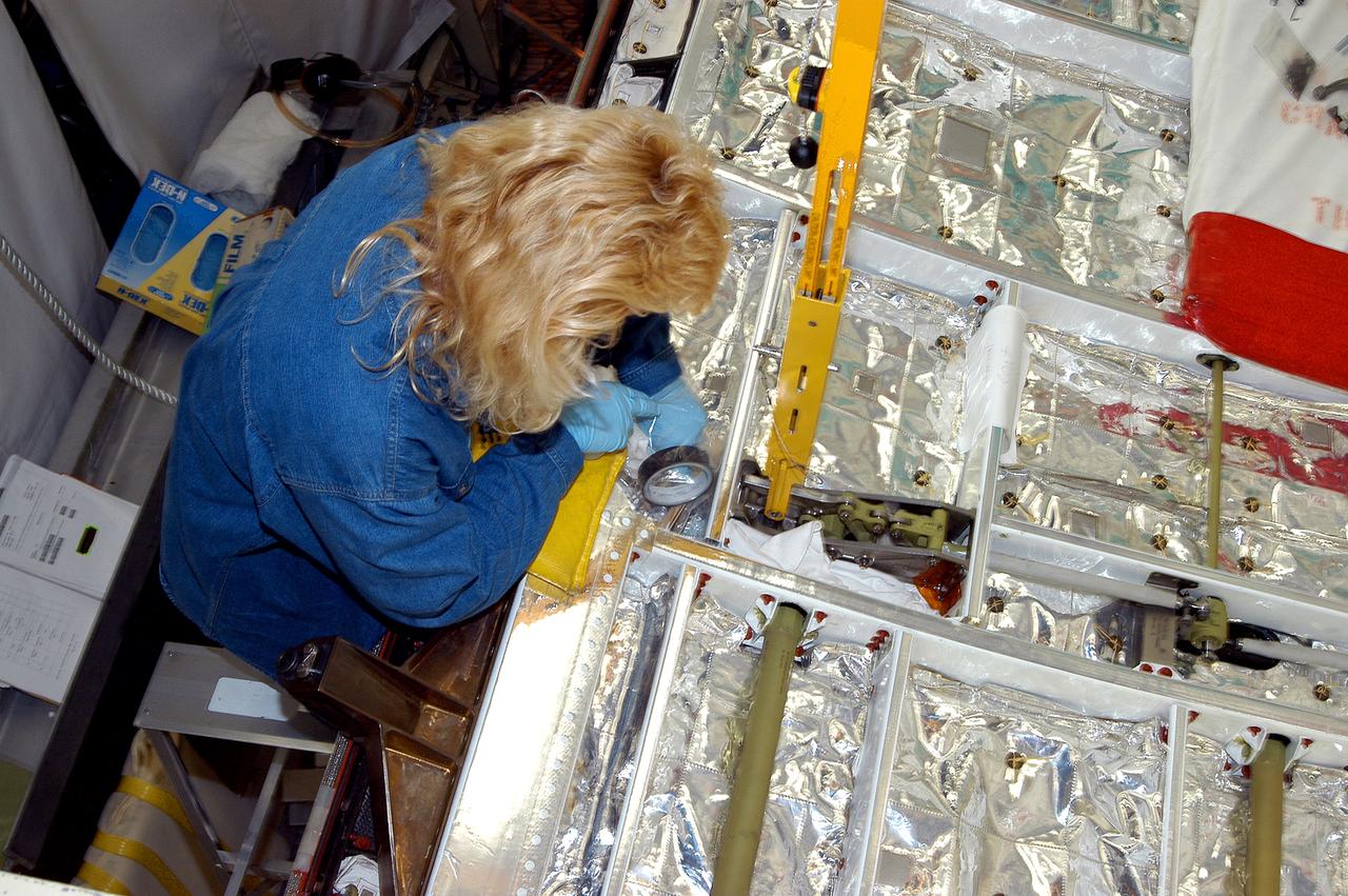 KENNEDY SPACE CENTER, FLA. -  A worker in the Orbiter Processing Facility checks part of the payload bay on Discovery.  The orbiter recently underwent an Orbiter Major Modification period, which included inspection, modifications and reservicing of most systems onboard. The work on Discovery also included the installation of a Multifunction Electronic Display Subsystem (MEDS) - a state-of-the-art “glass cockpit.”  The orbiter is now being prepared for eventual launch on a future mission.