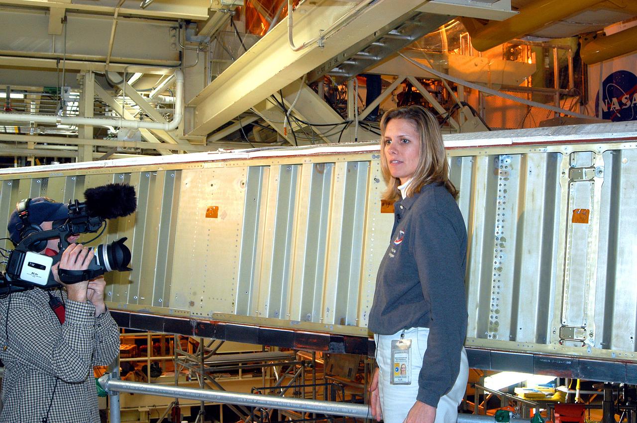 KENNEDY SPACE CENTER, FLA. -  In the Orbiter Processing Facility, Stephanie Stilson, NASA vehicle manager for Discovery, stands in front of a leading edge on the wing of Discovery.  She is being filmed for a special feature on the KSC Web about the recent Orbiter Major Modification period on Discovery, which included inspection, modifications and reservicing of most systems onboard, plus installation of a Multifunction Electronic Display Subsystem (MEDS) - a state-of-the-art “glass cockpit.”  The orbiter is now being prepared for eventual launch on a future mission.