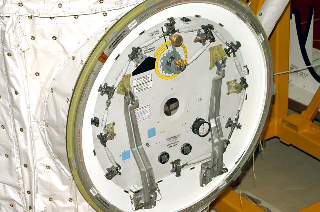 NASA image: KENNEDY SPACE CENTER, FLA. -  Seen in the photo is one end of the airlock that is installed in the payload bay of orbiter Discovery.  The airlock is normally located inside the middeck of the spacecraft’s pressurized crew cabin. The airlock is sized to accommodate two fully suited flight crew members simultaneously. Support functions include airlock depressurization and repressurization, extravehicular activity equipment recharge, liquid-cooled garment water cooling, EVA equipment checkout, donning and communications. The outer hatch isolates the airlock from the unpressurized payload bay when closed and permits the EVA crew members to exit from the airlock to the payload bay when open.