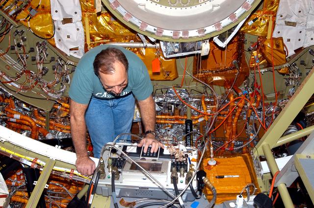 NASA image: KENNEDY SPACE CENTER, FLA. -  In the Orbiter Processing Facility, a worker checks out part of the equipment in the airlock, at one end of Discovery’s payload bay.  The airlock is sized to accommodate two fully suited flight crew members simultaneously. Support functions include airlock depressurization and repressurization, extravehicular activity equipment recharge, liquid-cooled garment water cooling, EVA equipment checkout, donning and communications. The outer hatch isolates the airlock from the unpressurized payload bay when closed and permits the EVA crew members to exit from the airlock to the payload bay when open.