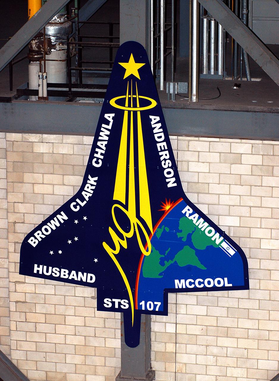 KENNEDY SPACE CENTER, FLA. -  A 20-foot by 15-foot replica of the STS-107 logo has been installed above the “A” on the A tower in the transfer aisle of the Vehicle Assembly Building.  The debris from the orbiter Columbia, lost in a tragic accident on its return to Earth from the STS-107 mission, is permanently stored in the tower.  A dedication ceremony Jan. 29, 2004, unveiled a plaque being installed in the storage area in honor of “Columbia, the crew of STS-107, and their loved ones.”