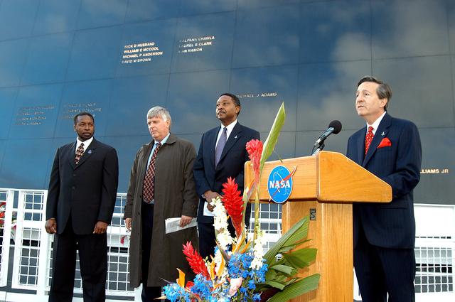 NASA image: KENNEDY SPACE CENTER, FLA. -  At the podium in front of the Space Memorial Mirror at the KSC Visitor Complex is Dr. Stephen Feldman, president of the Astronaut Memorial Foundation.  He spoke to attendees at the memorial service remembering and honoring the crew of Columbia.  With him (from left) are KSC Deputy Director Woodrow Whitlow Jr., Center Director Jim Kennedy and Executive Director of Florida Space Authority Winston Scott.   Feb. 1 is the one-year anniversary of the loss of the crew and orbiter Columbia in a tragic accident as the ship returned to Earth following mission STS-107.  Scott is a former astronaut who flew on Columbia in 1997.  Attended by many friends, co-workers and families, the memorial service was also open to the public.