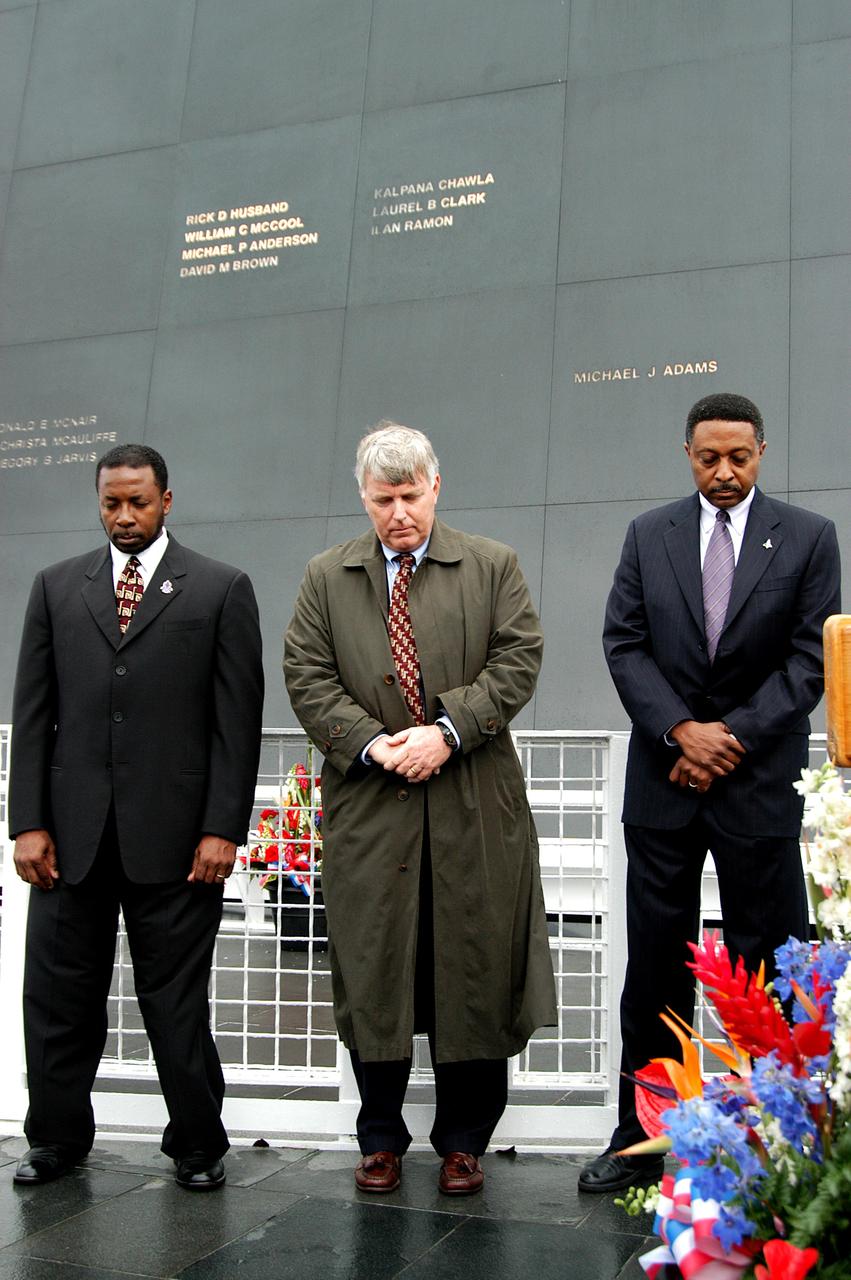 KENNEDY SPACE CENTER, FLA. -  Standing in front of the Space Memorial Mirror at the KSC Visitor Complex, KSC Deputy Director Woodrow Whitlow Jr., Center Director Jim Kennedy and Executive Director of Florida Space Authority Winston Scott bow their heads in prayer during a memorial service remembering and honoring the crew of Columbia.  Feb. 1 is the one-year anniversary of the loss of the crew and orbiter Columbia in a tragic accident as the ship returned to Earth following mission STS-107.  Scott is a former astronaut who flew on Columbia in 1997. The public was also invited to the memorial service.