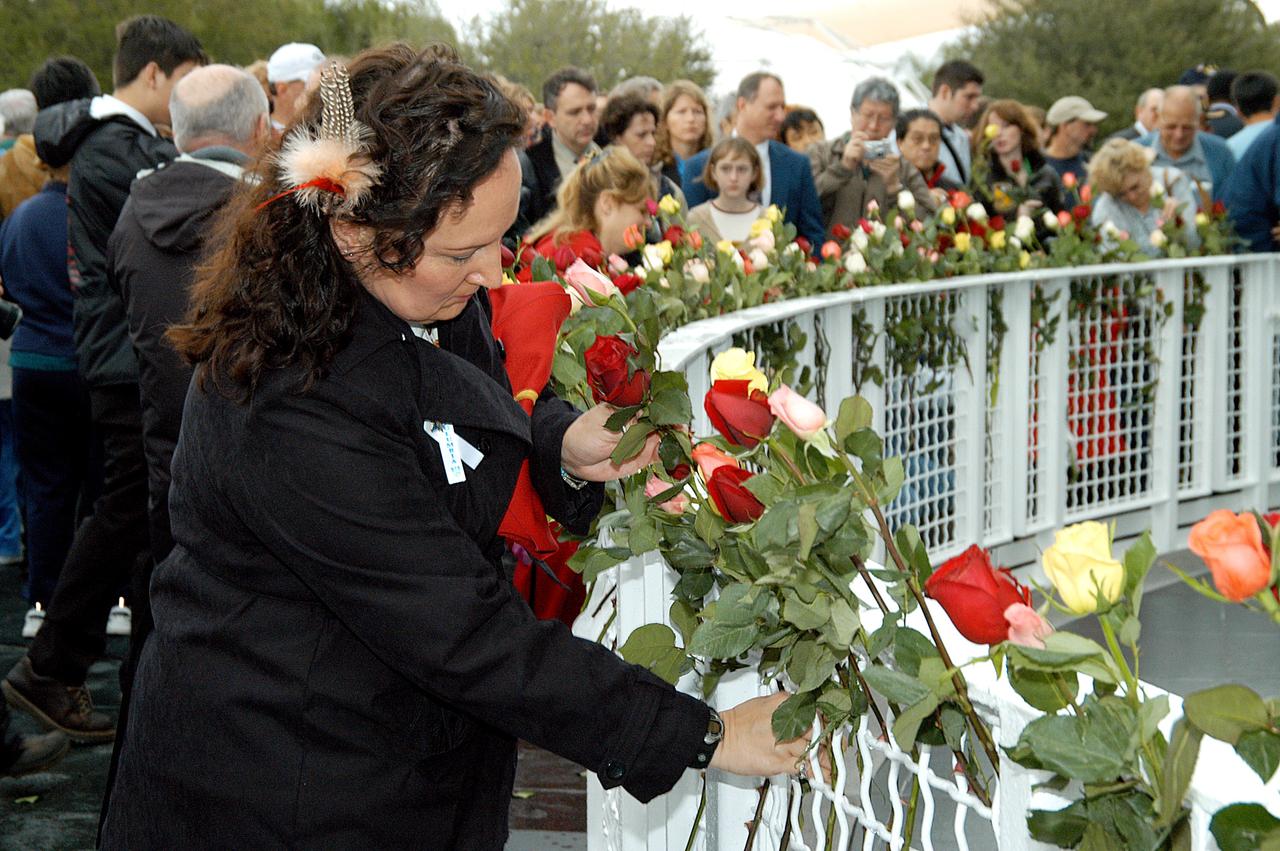 KENNEDY SPACE CENTER, FLA. - Following the memorial service for the crew of Columbia at the Space Memorial Mirror, Louise Kleba, who is with United Space Alliance, joins other visitors placing roses in the wire mesh fence surrounding the mirror.  Feb. 1 is the one-year anniversary of the loss of the crew and orbiter Columbia in a tragic accident as the ship returned to Earth following mission STS-107. The public was invited to the memorial service, held in the KSC Visitor Complex, which included comments by Center Director Jim Kennedy and Executive Director of Florida Space Authority Winston Scott.  Scott is a former astronaut who flew on Columbia in 1997.