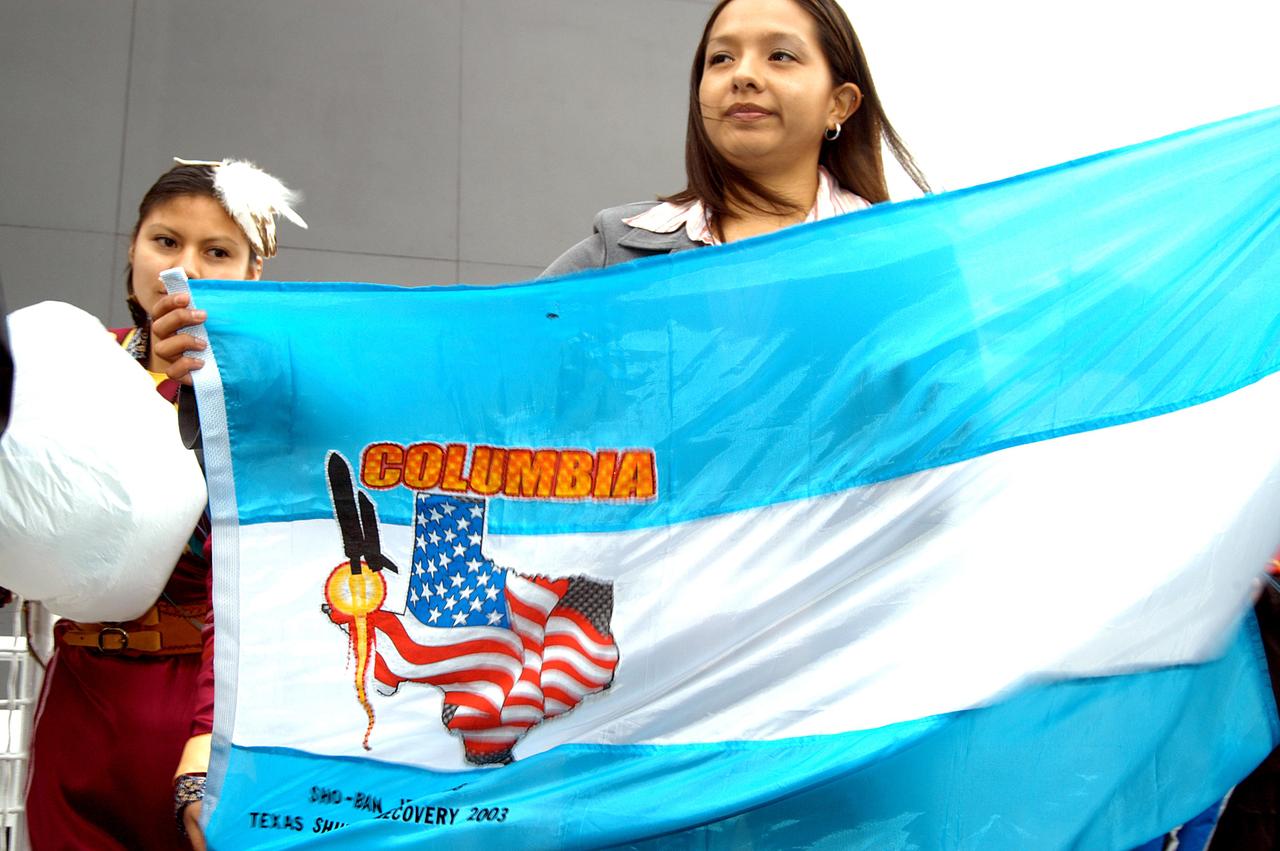 KENNEDY SPACE CENTER, FLA. - Some of the dancers from the Shoshone-Bannock Junior-Senior High School, Fort Hall, Idaho, hold a flag commemorating the orbiter Columbia and her crew.  The dancers performed a healing ceremony during the memorial service held at the Space Memorial Mirror for the crew of Columbia.  Students and staff of the Shoshone-Bannock Nation had an experiment on board Columbia.  Feb. 1 is the one-year anniversary of the loss of the crew and orbiter Columbia in a tragic accident as the ship returned to Earth following mission STS-107. The public was invited to the memorial service, held in the KSC Visitor Complex, which included comments by Center Director Jim Kennedy and Executive Director of Florida Space Authority Winston Scott.  Scott is a former astronaut who flew on Columbia in 1997.