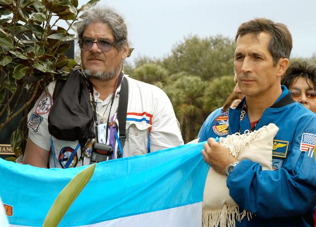NASA image: KENNEDY SPACE CENTER, FLA. - Astronaut John Herrington (right) holds part of a flag presented by dancers from the Shoshone-Bannock Junior-Senior High School, Fort Hall, Idaho, commemorating the orbiter Columbia and her crew.  The dancers performed a healing ceremony during the memorial service held at the Space Memorial Mirror for the crew of Columbia.  Feb. 1 is the one-year anniversary of the loss of the crew and orbiter Columbia in a tragic accident as the ship returned to Earth following mission STS-107.  Students and staff of the Shoshone-Bannock Nation had an experiment on board Columbia. The public was invited to the memorial service, held in the KSC Visitor Complex, which included comments by Center Director Jim Kennedy and Executive Director of Florida Space Authority Winston Scott.  Scott is a former astronaut who flew on Columbia in 1997.