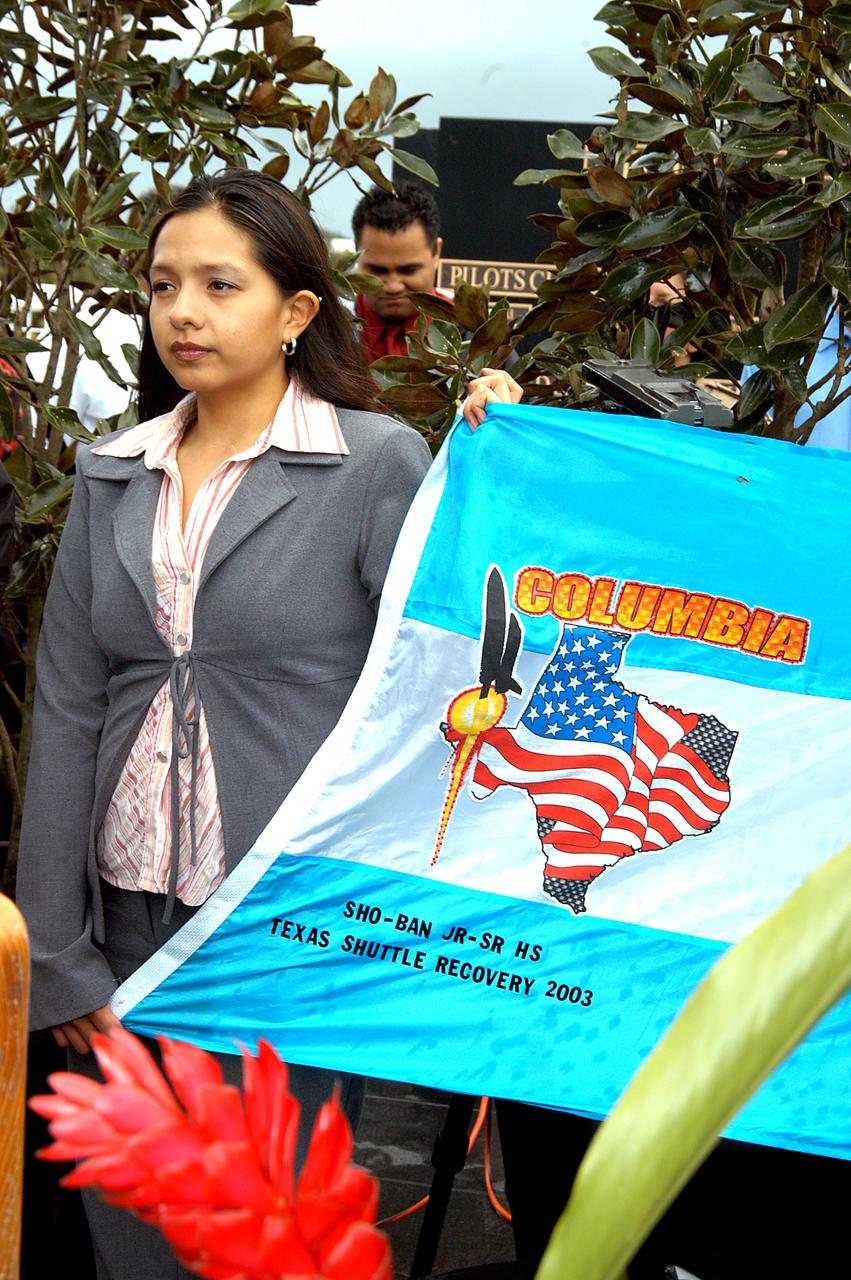 KENNEDY SPACE CENTER, FLA. - A student from Shoshone-Bannock Junior-Senior High School, Fort Hall, Idaho, holds part of a flag presented by dancers from the Shoshone-Bannock Native American community, Fort Hall, Idaho, commemorating the orbiter Columbia and her crew.  The dancers performed a healing ceremony during the memorial service held at the Space Memorial Mirror for the crew of Columbia.  Feb. 1 is the one-year anniversary of the loss of the crew and orbiter Columbia in a tragic accident as the ship returned to Earth following mission STS-107.  Students and staff of the Shoshone-Bannock Nation had an experiment on board Columbia. The public was invited to the memorial service, held in the KSC Visitor Complex, which included comments by Center Director Jim Kennedy and Executive Director of Florida Space Authority Winston Scott.  Scott is a former astronaut who flew on Columbia in 1997.