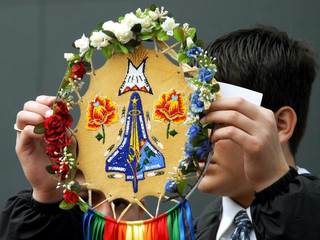 NASA image: KENNEDY SPACE CENTER, FLA. - A member of the Shoshone-Bannock Native American community from Fort Hall, Idaho, displays a handmade item with the STS-107 logo.  Dancers from Shoshone-Bannock Junior-Senior High School performed a healing ceremony during the memorial held at the Space Memorial Mirror, in the KSC Visitor Complex.  Feb. 1 is the one-year anniversary of the loss of the crew and orbiter Columbia in a tragic accident as the ship returned to Earth following mission STS-107.  Students and staff of the Shoshone-Bannock Nation had an experiment on board Columbia. The public was invited to the memorial service, held in the KSC Visitor Complex, which included comments by Center Director Jim Kennedy and Executive Director of Florida Space Authority Winston Scott.  Scott is a former astronaut who flew on Columbia in 1997.