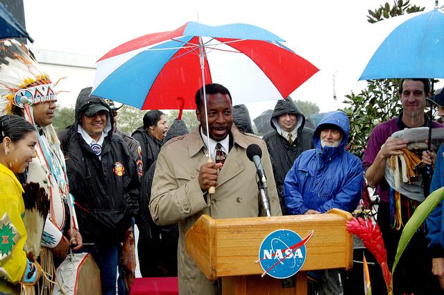 NASA image: KENNEDY SPACE CENTER, FLA. - KSC Deputy Director Woodrow Whitlow Jr. closes the memorial service held for the crew of Columbia at the Space Memorial Mirror in the KSC Visitor Complex.  He is surrounded by dancers of the Shoshone-Bannock Native American community who performed a healing ceremony during the memorial.  Feb. 1 is the one-year anniversary of the loss of the crew and orbiter Columbia in a tragic accident as the ship returned to Earth following mission STS-107.  Students and staff of the Shoshone-Bannock Nation had an experiment on board Columbia. The public was invited to the memorial service, held in the KSC Visitor Complex, which included comments by Center Director Jim Kennedy and Executive Director of Florida Space Authority Winston Scott.  Scott is a former astronaut who flew on Columbia in 1997.