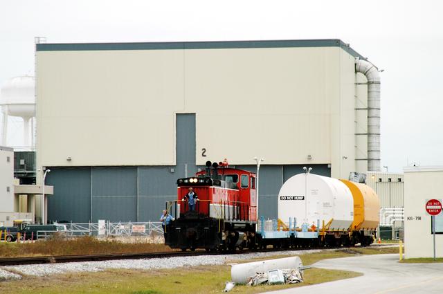 NASA image: KENNEDY SPACE CENTER, FLA. - The red NASA engine backs up with its cargo of containers in order to change tracks.  The containers enclose segments of a solid rocket booster being returned to Utah for testing.  The segments were part of the STS-114 stack.  It is the first time actual flight segments that had been stacked for flight in the VAB are being returned for testing.  They will undergo firing, which will enable inspectors to check the viability of the solid and verify the life expectancy for stacked segments.