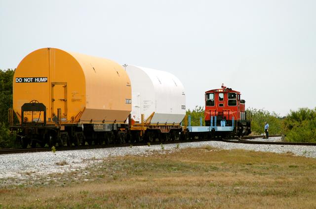 NASA image: KENNEDY SPACE CENTER, FLA. - The red NASA engine hauls its cargo toward Titusville, Fla. The containers enclose segments of a solid rocket booster being returned to Utah for testing.  The segments were part of the STS-114 stack.  It is the first time actual flight segments that had been stacked for flight in the VAB are being returned for testing.  They will undergo firing, which will enable inspectors to check the viability of the solid and verify the life expectancy for stacked segments.