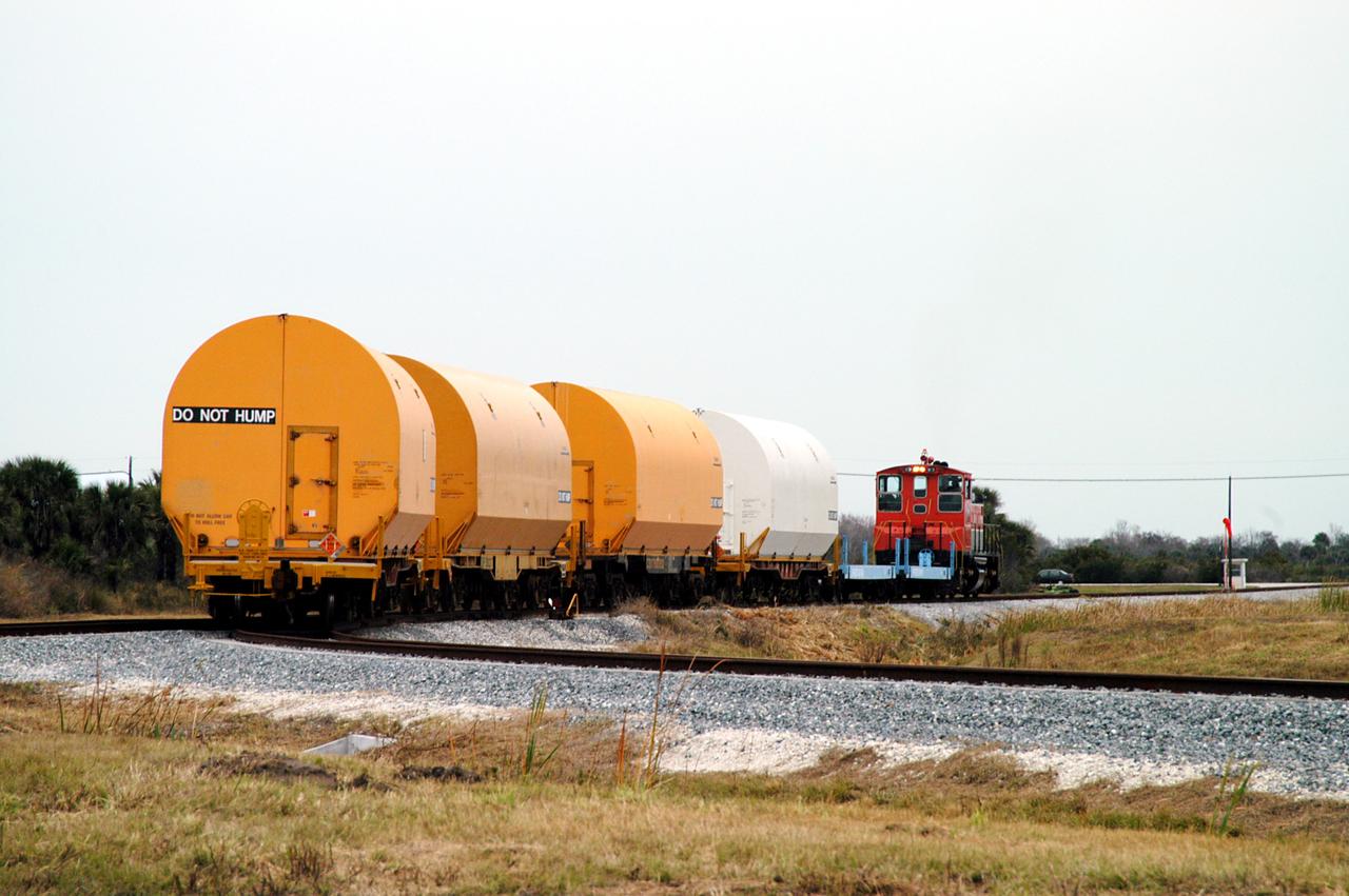 KENNEDY SPACE CENTER, FLA. - The red NASA engine hauls its cargo toward Titusville, Fla. The containers enclose segments of a solid rocket booster being returned to Utah for testing.  The segments were part of the STS-114 stack.  It is the first time actual flight segments that had been stacked for flight in the VAB are being returned for testing.  They will undergo firing, which will enable inspectors to check the viability of the solid and verify the life expectancy for stacked segments.