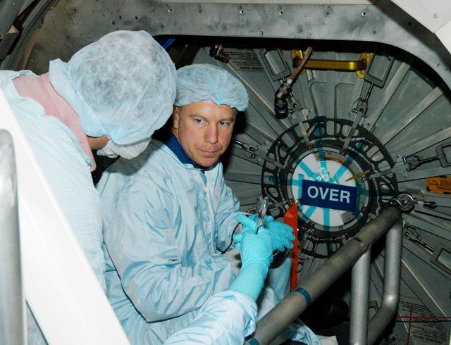 KENNEDY SPACE CENTER, FLA. - Astronaut Tim Kopra (facing camera) aids in Intravehicular Activity (IVA) constraints testing on the Italian-built Node 2, a future element of the International Space Station.  The second of three Station connecting modules, the Node 2 attaches to the end of the U.S. Lab and provides attach locations for several other elements.  Kopra is currently assigned technical duties in the Space Station Branch of the Astronaut Office, where his primary focus involves the testing of crew interfaces for two future ISS modules as well as the implementation of support computers and operational Local Area Network on ISS.   Node 2 is scheduled to launch on mission STS-120, Station assembly flight 10A.