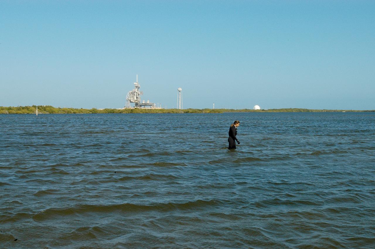 KENNEDY SPACE CENTER, FLA. - Karen Holloway-Adkins, KSC wildlife specialist, searches the Banana River for a grass specimen. In the background is one of the launch pads.  The biologist is studying the life history of sea turtles, especially what they eat, where they lay their eggs and what factors might harm their survival.  On the boat trip she is also monitoring the growth of sea grasses and algae and the water quality of estuaries and lagoons used by sea turtles and other aquatic wildlife.