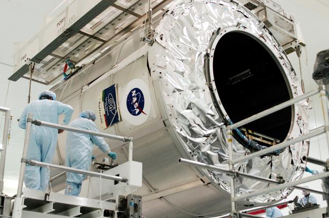 NASA image: KENNEDY SPACE CENTER, FLA. - Workers in the Space Station Processing Facility secure the Multi-Purpose Logistics Module Raffaello onto a new work stand.  Raffaello is the second MPLM built by the Italian Space Agency, serving as a reusable logistics carrier and primary delivery system to resupply and return station cargo requiring a pressurized environment.  It has been moved to allow the third MPLM, Donatello, to be brought in for routine testing.  Donatello has been stored in the Operations and Checkout Building.  This is the first time all three MPLMs are in the SSPF; the other one is the Leonardo.  Raffaello is scheduled to fly on Space Shuttle Atlantis on mission STS-114.