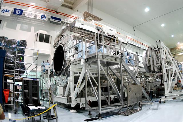 NASA image: KENNEDY SPACE CENTER, FLA. - Workers in the Space Station Processing Facility prepare to release the overhead crane from the Multi-Purpose Logistics Module Raffaello now secure on a new work stand.  Raffaello is the second MPLM built by the Italian Space Agency, serving as a reusable logistics carrier and primary delivery system to resupply and return station cargo requiring a pressurized environment.  It has been moved to allow the third MPLM, Donatello, to be brought in for routine testing.  Donatello has been stored in the Operations and Checkout Building.  This is the first time all three MPLMs are in the SSPF; the other one is the Leonardo.  Raffaello is scheduled to fly on Space Shuttle Atlantis on mission STS-114.