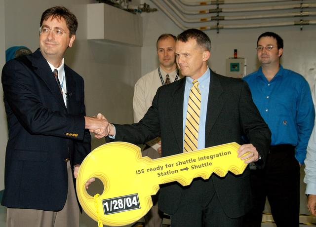 KENNEDY SPACE CENTER, FLA. - In a brief ceremony in the Space Station Processing Facility, Chuck Hardison (left), Boeing senior truss manager, turns over the “key” for the starboard truss segment S3/S4 to Scott Gahring, ISS Vehicle Office manager (acting), Johnson Space Center.  The trusses are scheduled to be delivered to the International Space Station on mission STS-117.
