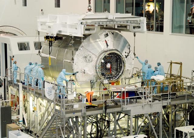 NASA image: KENNEDY SPACE CENTER, FLA. - In the Space Station Processing Facility,  workers help the Multi-Purpose Logistics Module Donatello settle onto a work stand.  Previously housed in the Operations and Checkout Building, Donatello was brought into the SSPF for routine testing.  This is the first time all three MPLMs (Donatello, Raffaello and Leonardo) are in the SSPF.  The MPLMs were built by the Italian Space Agency, to serve as reusable logistics carriers and the primary delivery system to resupply and return station cargo requiring a pressurized environment.  The third MPLM, Raffaello, is scheduled to fly on Space Shuttle Atlantis on mission STS-114.