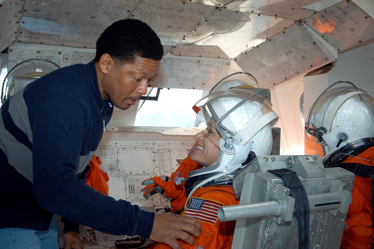KENNEDY SPACE CENTER, FLA. - Volunteers from the KSC Fire-Rescue team dressed in launch and entry suits settle into seats in an orbiter crew compartment mock-up under the guidance of George Brittingham, USA suit technician on the Closeout Crew. Brittingham is helping Catherine Di Biase, a nurse with Bionetics Life Sciences. They are all taking part in a “Mode VII” emergency landing simulation at Kennedy Space Center.  The purpose is to exercise emergency preparedness personnel, equipment and facilities in rescuing astronauts from a downed orbiter and providing immediate medical attention.  This simulation presents an orbiter that has crashed short of the Shuttle Landing Facility in a wooded area 2-1/2 miles south of Runway 33.  Emergency crews will respond to the volunteer “astronauts” simulating various injuries.  Rescuers must remove the crew, provide triage and transport to hospitals those who need further treatment.  Local hospitals are participating in the exercise.