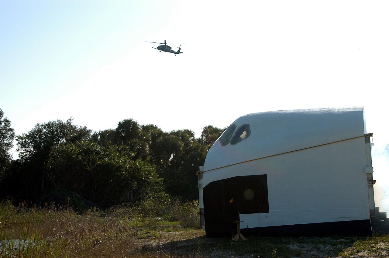KENNEDY SPACE CENTER, FLA. - A helicopter approaches an orbiter crew compartment mock-up as part of a “Mode VII” emergency landing simulation at Kennedy Space Center.  The purpose is to exercise emergency preparedness personnel, equipment and facilities in rescuing astronauts from a downed orbiter and providing immediate medical attention.  This simulation presents an orbiter that has crashed short of the Shuttle Landing Facility in a wooded area 2-1/2 miles south of Runway 33.  Emergency crews will respond to the volunteer “astronauts” simulating various injuries.  Rescuers must remove the crew, provide triage and transport to hospitals those who need further treatment.  Local hospitals are participating in the exercise.