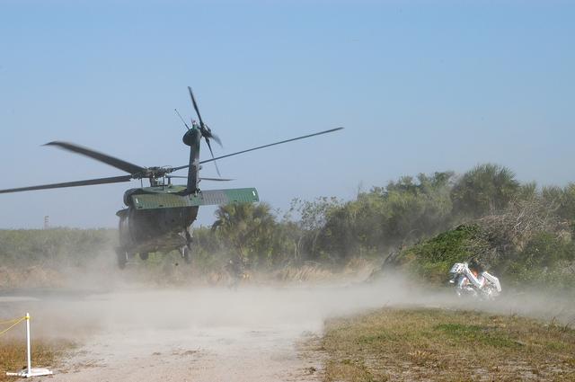 NASA image: KENNEDY SPACE CENTER, FLA. - A helicopter is landing near rescue team members taking part in a “Mode VII” emergency landing simulation at Kennedy Space Center.  The purpose of Mode VII is to exercise emergency preparedness personnel, equipment and facilities in rescuing astronauts from a downed orbiter and providing immediate medical attention.  This simulation presents an orbiter that has crashed short of the Shuttle Landing Facility in a wooded area 2-1/2 miles south of Runway 33.  Emergency crews are responding to the volunteer “astronauts” simulating various injuries inside an orbiter crew compartment mock-up.  Rescuers must remove the crew, provide triage and transport to hospitals those who need further treatment.  Local hospitals are participating in the exercise.