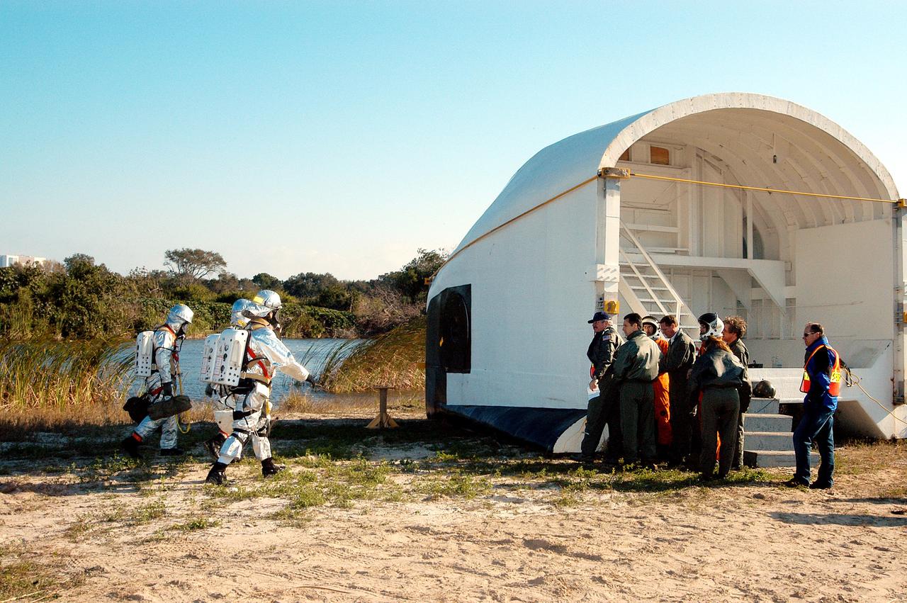 KENNEDY SPACE CENTER, FLA. - Emergency crew members return to the orbiter crew compartment mock-up that is the scene of a “Mode VII” emergency landing simulation at Kennedy Space Center.  The purpose of the Mode VII is to exercise emergency preparedness personnel, equipment and facilities in rescuing astronauts from a downed orbiter and providing immediate medical attention.  This simulation presents an orbiter that has crashed short of the Shuttle Landing Facility in a wooded area 2-1/2 miles south of Runway 33.  Emergency crews are responding to the volunteer “astronauts” simulating various injuries inside the mock-up compartment.  Rescuers have had to remove the crew, provide triage and transport to hospitals those who need further treatment.  Local hospitals are participating in the exercise.