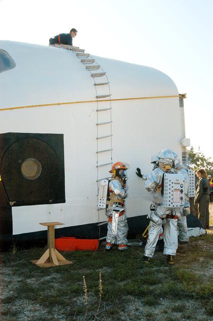 NASA image: KENNEDY SPACE CENTER, FLA. - Emergency crew members prepare to rescue another “astronaut” from inside the orbiter crew compartment mock-up that is the scene of a “Mode VII” emergency landing simulation at Kennedy Space Center.  The purpose of the Mode VII is to exercise emergency preparedness personnel, equipment and facilities in rescuing astronauts from a downed orbiter and providing immediate medical attention.  This simulation presents an orbiter that has crashed short of the Shuttle Landing Facility in a wooded area 2-1/2 miles south of Runway 33.  Emergency crews are responding to the volunteer astronauts who are simulating various injuries.  Rescuers must remove the crew, provide triage and transport to hospitals those who need further treatment.  Local hospitals are participating in the exercise.