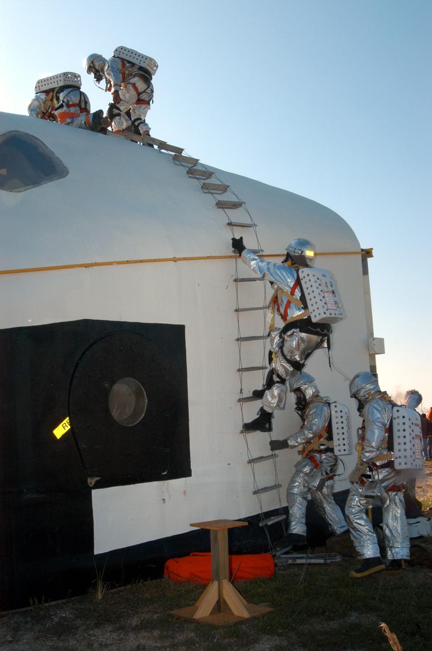 KENNEDY SPACE CENTER, FLA. - Emergency crew members prepare to “rescue” another astronaut from inside the orbiter crew compartment mock-up that is the scene of a “Mode VII” emergency landing simulation at Kennedy Space Center.  The purpose of the Mode VII is to exercise emergency preparedness personnel, equipment and facilities in rescuing astronauts from a downed orbiter and providing immediate medical attention.  This simulation presents an orbiter that has crashed short of the Shuttle Landing Facility in a wooded area 2-1/2 miles south of Runway 33.  Emergency crews are responding to the volunteer “astronauts” who are simulating various injuries.  Rescuers must remove the crew, provide triage and transport to hospitals those who need further treatment.  Local hospitals are participating in the exercise.
