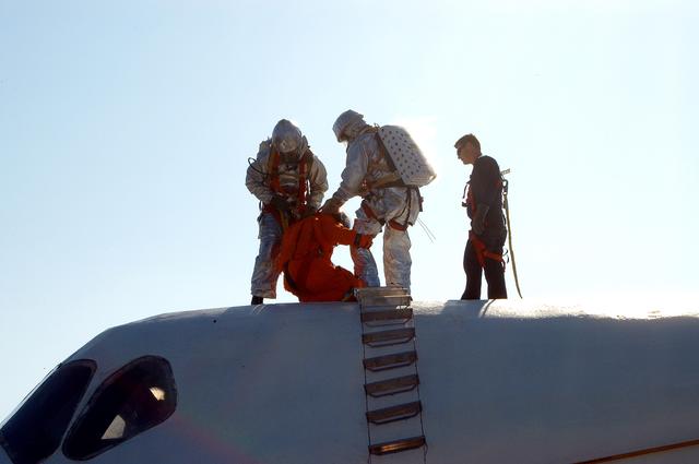 NASA image: KENNEDY SPACE CENTER, FLA. - Emergency crew members “rescue” an astronaut from inside the orbiter crew compartment mock-up that is the scene of a “Mode VII” emergency landing simulation at Kennedy Space Center.  The purpose of the Mode VII is to exercise emergency preparedness personnel, equipment and facilities in rescuing astronauts from a downed orbiter and providing immediate medical attention.  This simulation presents an orbiter that has crashed short of the Shuttle Landing Facility in a wooded area 2-1/2 miles south of Runway 33.  Emergency crews are responding to the volunteer “astronauts” who are simulating various injuries.  Rescuers must remove the crew, provide triage and transport to hospitals those who need further treatment.  Local hospitals are participating in the exercise.