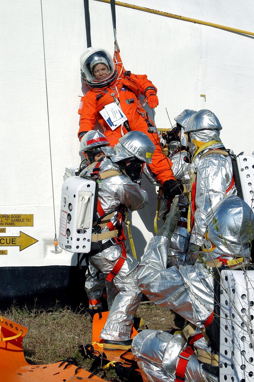 KENNEDY SPACE CENTER, FLA. - Emergency crew members on the ground take hold of a volunteer “astronaut” lowered from the top of the orbiter crew compartment mock-up that is the scene of a “Mode VII” emergency landing simulation at Kennedy Space Center.  The purpose of the Mode VII is to exercise emergency preparedness personnel, equipment and facilities in rescuing astronauts from a downed orbiter and providing immediate medical attention.  This simulation presents an orbiter that has crashed short of the Shuttle Landing Facility in a wooded area 2-1/2 miles south of Runway 33.  Emergency crews are responding to the volunteer astronauts who are simulating various injuries.  Rescuers must remove the crew, provide triage and transport to hospitals those who need further treatment.  Local hospitals are participating in the exercise.