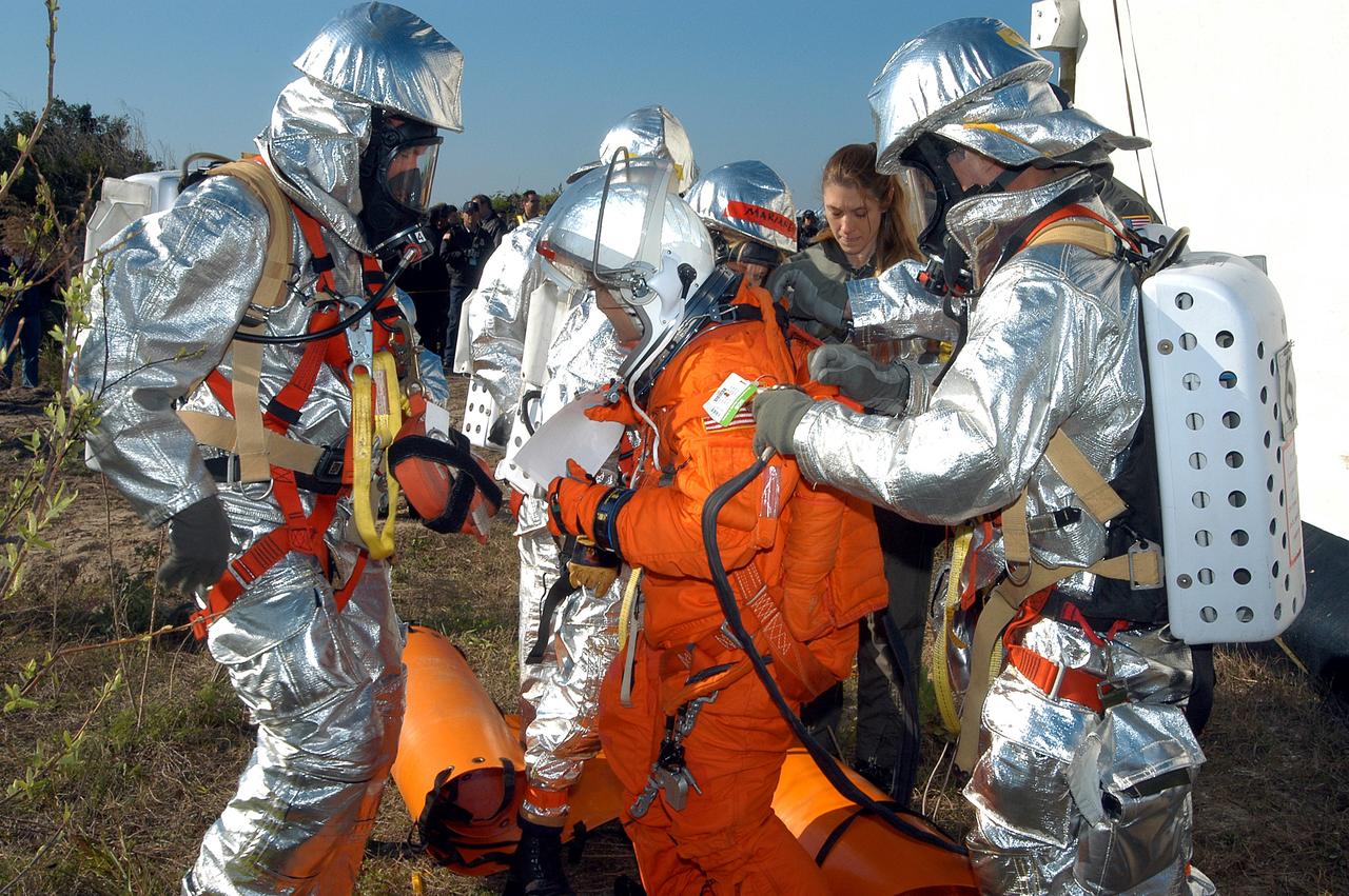KENNEDY SPACE CENTER, FLA. - Emergency crew members help a volunteer “astronaut” onto the ground after being lowered from the top of the orbiter crew compartment mock-up that is the scene of a “Mode VII” emergency landing simulation at Kennedy Space Center.  The purpose of the Mode VII is to exercise emergency preparedness personnel, equipment and facilities in rescuing astronauts from a downed orbiter and providing immediate medical attention.  This simulation presents an orbiter that has crashed short of the Shuttle Landing Facility in a wooded area 2-1/2 miles south of Runway 33.  Emergency crews are responding to the volunteer astronauts who are simulating various injuries.  Rescuers must remove the crew, provide triage and transport to hospitals those who need further treatment.  Local hospitals are participating in the exercise.