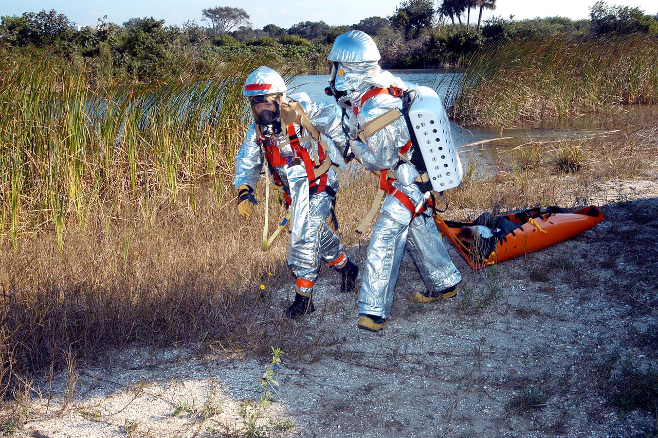 KENNEDY SPACE CENTER, FLA. - Emergency crew members transport an “injured” astronaut during a “Mode VII” emergency landing simulation at Kennedy Space Center.  The purpose of the Mode VII is to exercise emergency preparedness personnel, equipment and facilities in rescuing astronauts from a downed orbiter and providing immediate medical attention.  This simulation presents an orbiter that has crashed short of the Shuttle Landing Facility in a wooded area 2-1/2 miles south of Runway 33.  Emergency crews are responding to the volunteer astronauts who are simulating various injuries.  Rescuers must remove the crew, provide triage and transport to hospitals those who need further treatment.  Local hospitals are participating in the exercise.