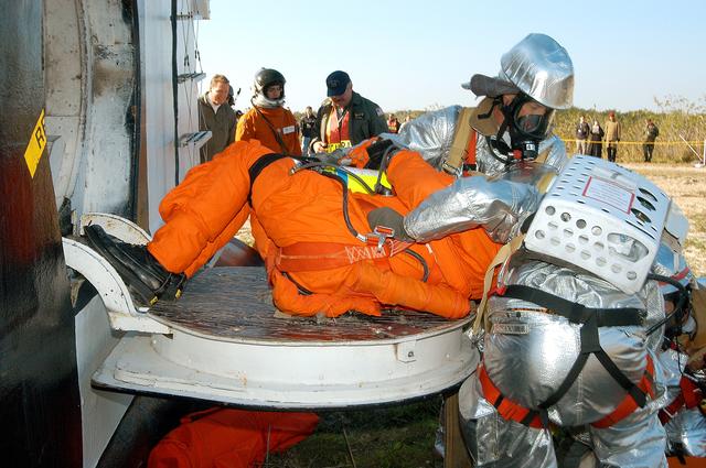 NASA image: KENNEDY SPACE CENTER, FLA. - Emergency crew members “rescue” an injured astronaut from the orbiter crew compartment mock-up during a “Mode VII” emergency landing simulation at Kennedy Space Center.  The purpose of the Mode VII is to exercise emergency preparedness personnel, equipment and facilities in rescuing astronauts from a downed orbiter and providing immediate medical attention.  This simulation presents an orbiter that has crashed short of the Shuttle Landing Facility in a wooded area 2-1/2 miles south of Runway 33.  Emergency crews are responding to the volunteer astronauts who are simulating various injuries.  Rescuers must remove the crew, provide triage and transport to hospitals those who need further treatment.  Local hospitals are participating in the exercise.