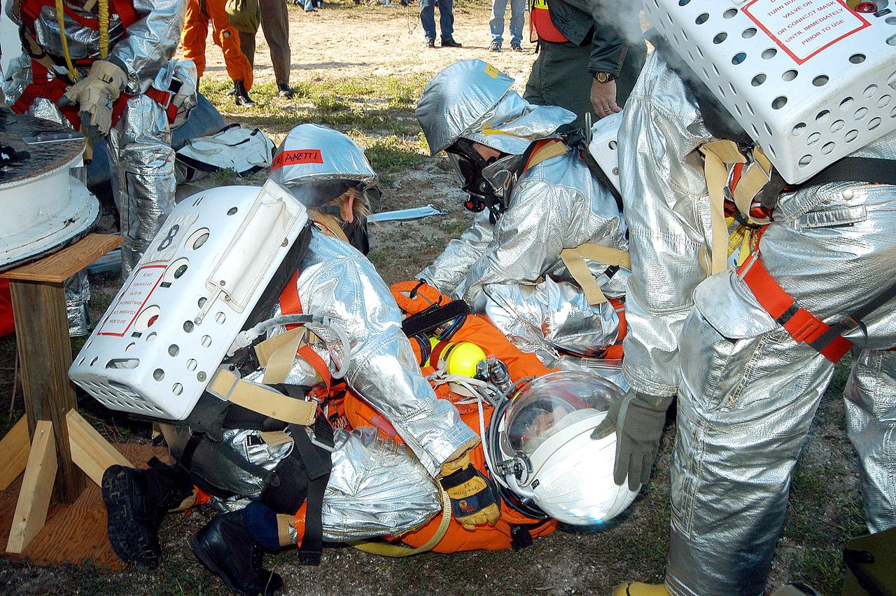 KENNEDY SPACE CENTER, FLA. - Emergency crew members help an injured astronaut after removing him from the orbiter crew compartment mock-up during a “Mode VII” emergency landing simulation at Kennedy Space Center.  The purpose of the Mode VII is to exercise emergency preparedness personnel, equipment and facilities in rescuing astronauts from a downed orbiter and providing immediate medical attention.  This simulation presents an orbiter that has crashed short of the Shuttle Landing Facility in a wooded area 2-1/2 miles south of Runway 33.  Emergency crews are responding to the volunteer astronauts who are simulating various injuries.  Rescuers must remove the crew, provide triage and transport to hospitals those who need further treatment.  Local hospitals are participating in the exercise.