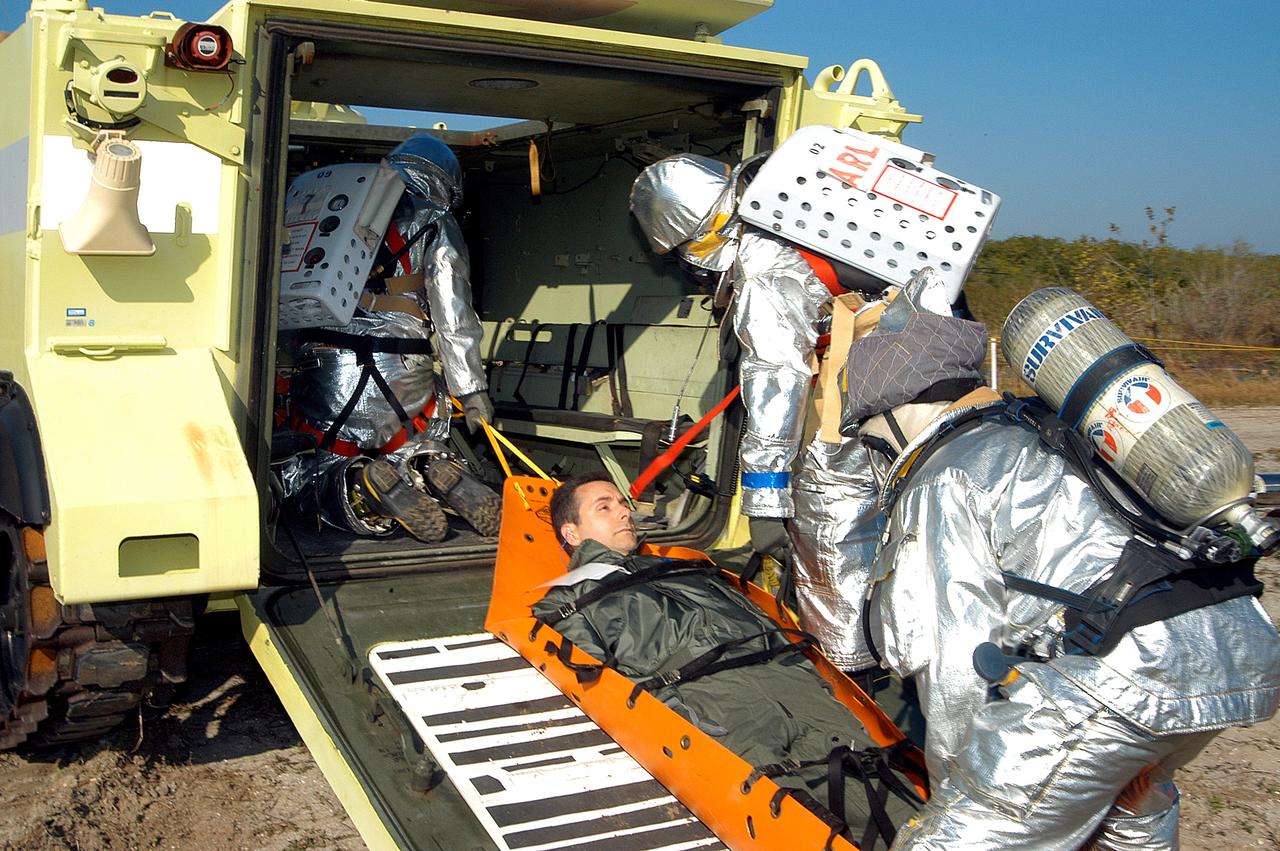 KENNEDY SPACE CENTER, FLA. - An “injured” rescue worker is lifted into an M-113 armored personnel carrier provided for transportation during a “Mode VII” emergency landing simulation at Kennedy Space Center.  The purpose of the Mode VII is to exercise emergency preparedness personnel, equipment and facilities in rescuing astronauts from a downed orbiter and providing immediate medical attention.  This simulation presents an orbiter that has crashed short of the Shuttle Landing Facility in a wooded area 2-1/2 miles south of Runway 33.  Emergency crews are responding to the volunteer astronauts who are simulating various injuries inside the crew compartment mock-up.  Rescuers must remove the crew, provide triage and transport to hospitals those who need further treatment.  Local hospitals are participating in the exercise.