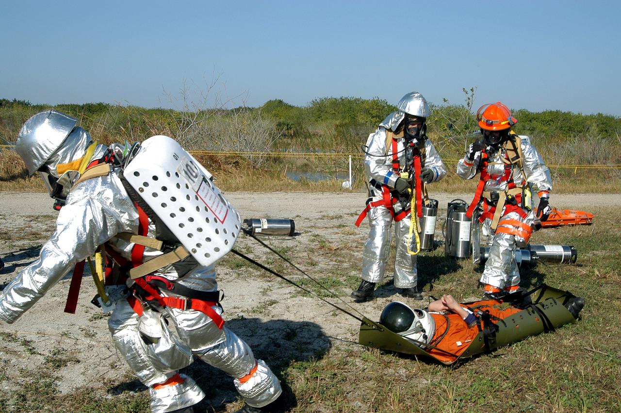 KENNEDY SPACE CENTER, FLA. - Emergency crew members transport an “injured”  astronaut during a “Mode VII” emergency landing simulation at Kennedy Space Center.  The purpose of the Mode VII is to exercise emergency preparedness personnel, equipment and facilities in rescuing astronauts from a downed orbiter and providing immediate medical attention.  This simulation presents an orbiter that has crashed short of the Shuttle Landing Facility in a wooded area 2-1/2 miles south of Runway 33.  Emergency crews are responding to the volunteer astronauts who are simulating various injuries inside the crew compartment mock-up.  Rescuers must remove the crew, provide triage and transport to hospitals those who need further treatment.  Local hospitals are participating in the exercise.