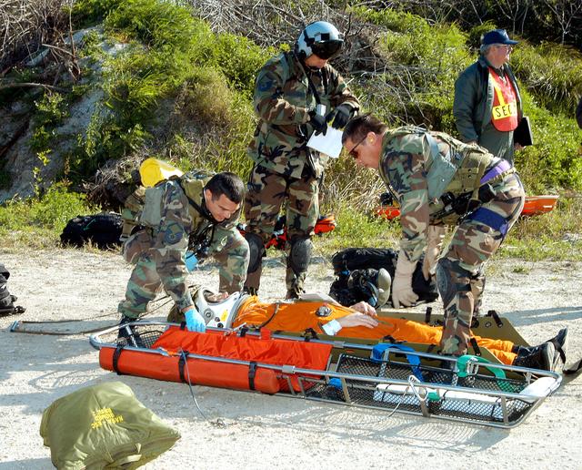 NASA image: KENNEDY SPACE CENTER, FLA. - A helicopter rescue team prepares another “injured” astronaut for transportation to a local hospital.  They are all taking part in a “Mode VII” emergency landing simulation at Kennedy Space Center.  The purpose of the Mode VII is to exercise emergency preparedness personnel, equipment and facilities in rescuing astronauts from a downed orbiter and providing immediate medical attention.  This simulation presents an orbiter that has crashed short of the Shuttle Landing Facility in a wooded area 2-1/2 miles south of Runway 33.  Emergency crews are responding to the volunteer “astronauts” who are simulating various injuries inside the crew compartment mock-up.  Rescuers must remove the crew, provide triage and transport to hospitals those who need further treatment.  Local hospitals are participating in the exercise.