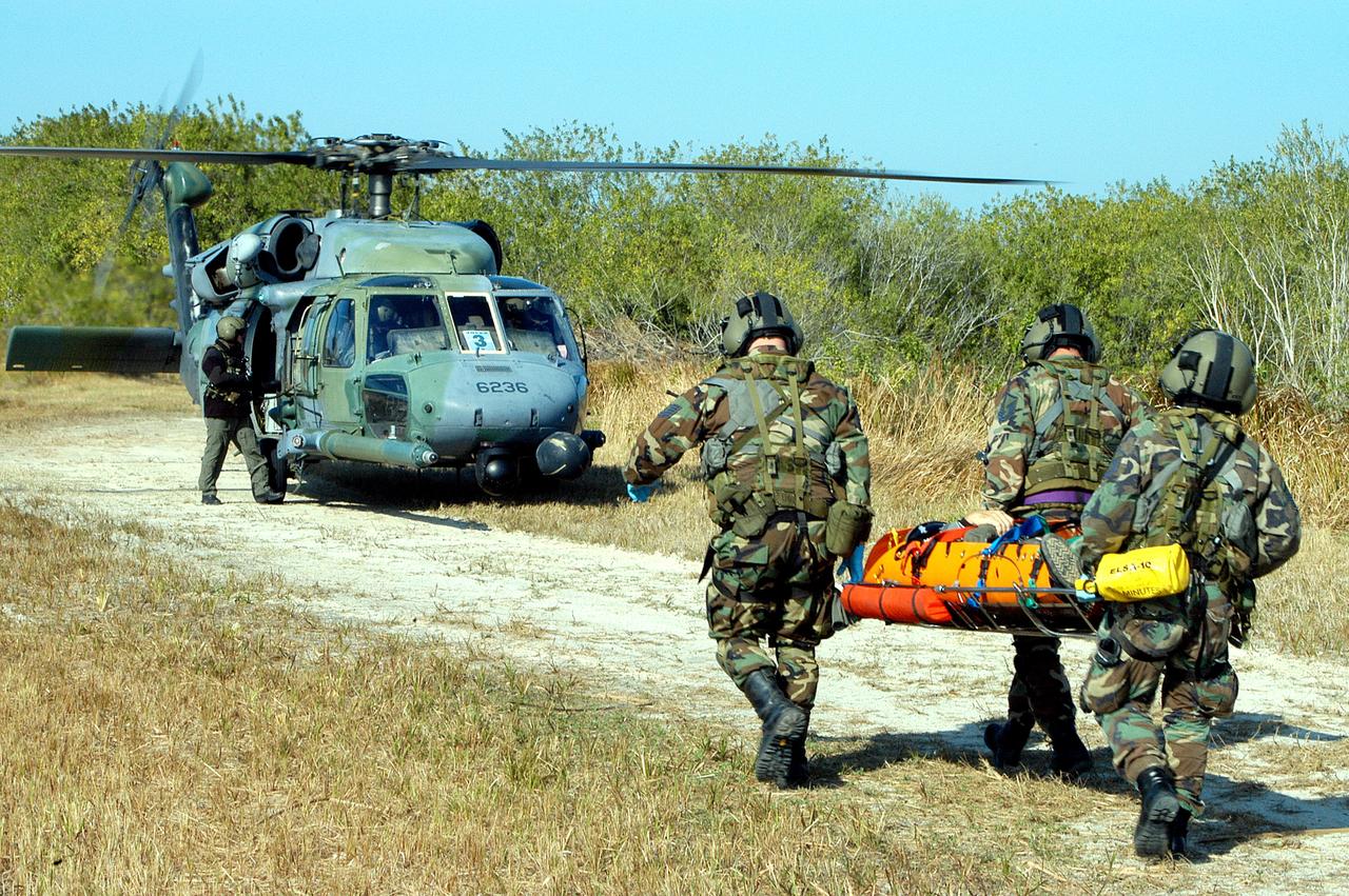 KENNEDY SPACE CENTER, FLA. - A helicopter rescue team carries another “injured” astronaut to a helicopter for transportation to a local hospital.  They are all taking part in a “Mode VII” emergency landing simulation at Kennedy Space Center.  The purpose of the Mode VII is to exercise emergency preparedness personnel, equipment and facilities in rescuing astronauts from a downed orbiter and providing immediate medical attention.  This simulation presents an orbiter that has crashed short of the Shuttle Landing Facility in a wooded area 2-1/2 miles south of Runway 33.  Emergency crews are responding to the volunteer “astronauts” who are simulating various injuries inside the crew compartment mock-up.  Rescuers must remove the crew, provide triage and transport to hospitals those who need further treatment.  Local hospitals are participating in the exercise.
