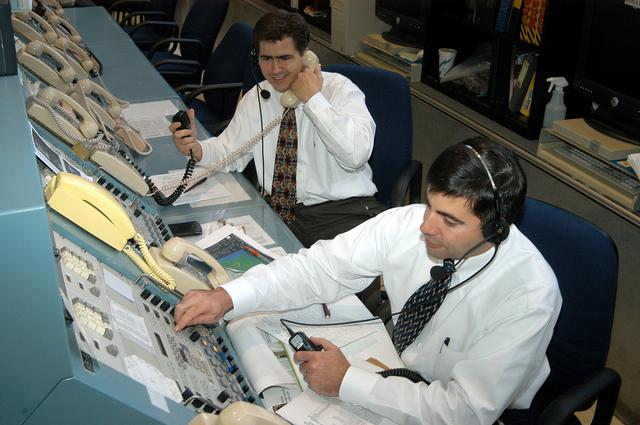 NASA image: KENNEDY SPACE CENTER, FLA. - In the Launch Control Center, Robert Holl (left),  Landing Recovery directo, and Donald Hammel, from the Shuttle Project Office, are in contact with the leaders of the “Mode VII” emergency landing simulation at Kennedy Space Center.  The simulation is being managed and directed from the LCC.  The purpose of the Mode VII is to exercise emergency preparedness personnel, equipment and facilities in rescuing astronauts from a downed orbiter and providing immediate medical attention.  This simulation presents an orbiter that has crashed short of the Shuttle Landing Facility in a wooded area 2-1/2 miles south of Runway 33.  Emergency crews are responding to the volunteer “astronauts” who are simulating various injuries inside the crew compartment mock-up.  Rescuers must remove the crew, provide triage and transport to hospitals those who need further treatment.  Local hospitals are participating in the exercise.