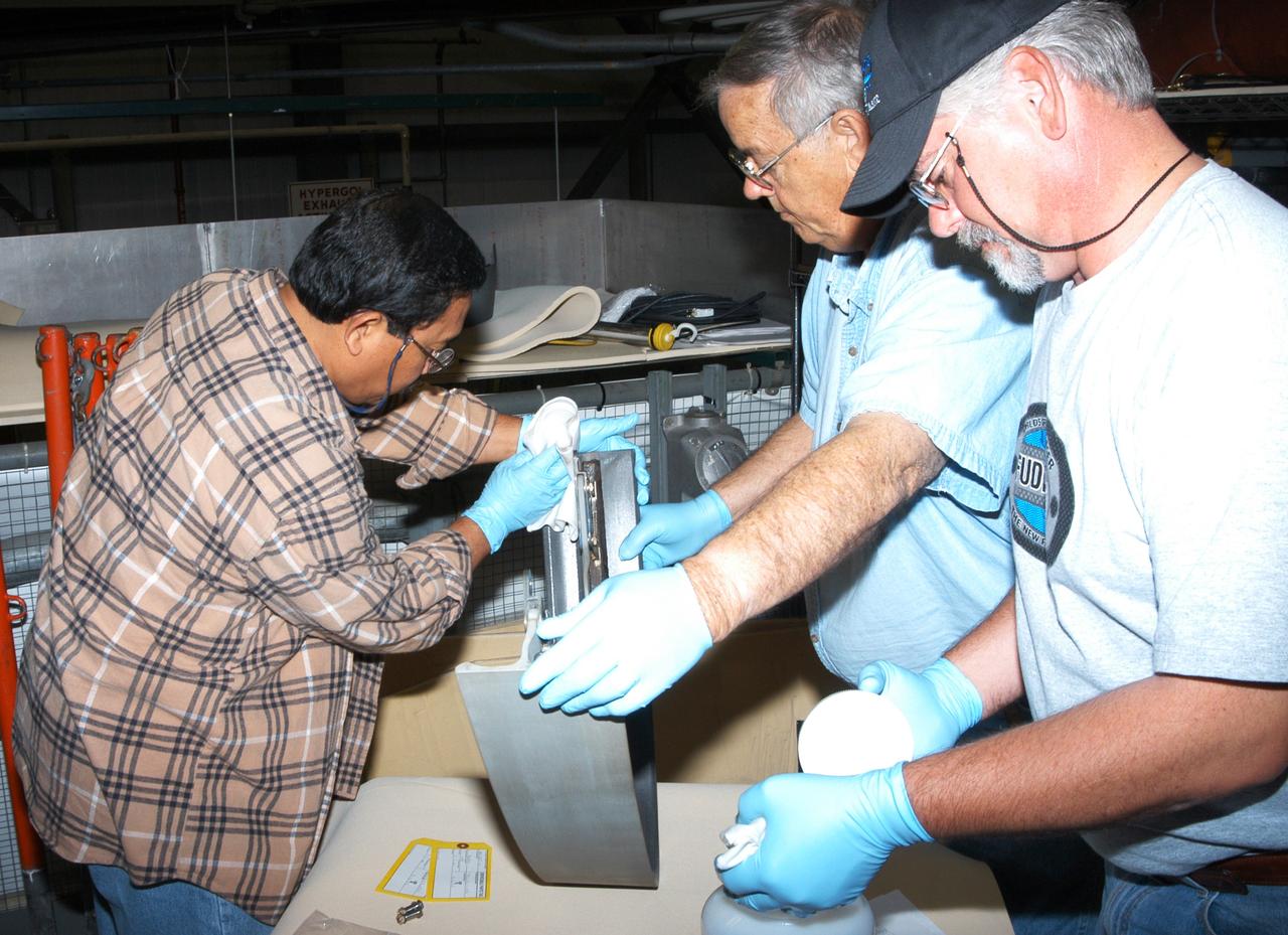 KENNEDY SPACE CENTER, FLA. - In the Orbiter Processing Facility, workers install C-shaped T-seals, which fit between each Reinforced Carbon Carbon panel, on the left-side wing leading edge of the orbiter Atlantis.