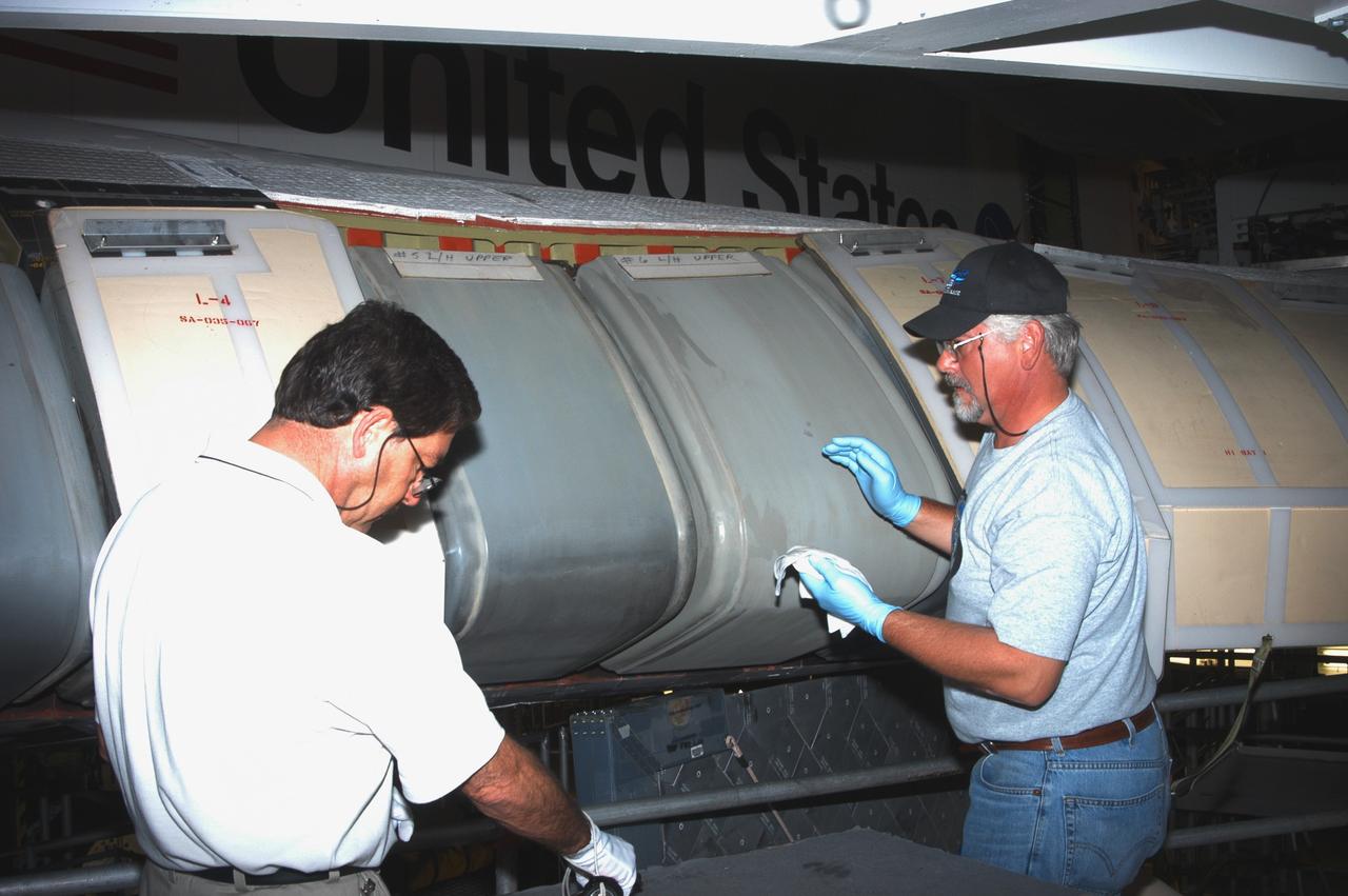 KENNEDY SPACE CENTER, FLA. - In the Orbiter Processing Facility, workers wipe down the Reinforced Carbon Carbon panels on Atlantis’ left-side wing leading edge in preparation for installing the C-shaped T-seals, which fit between each panel.