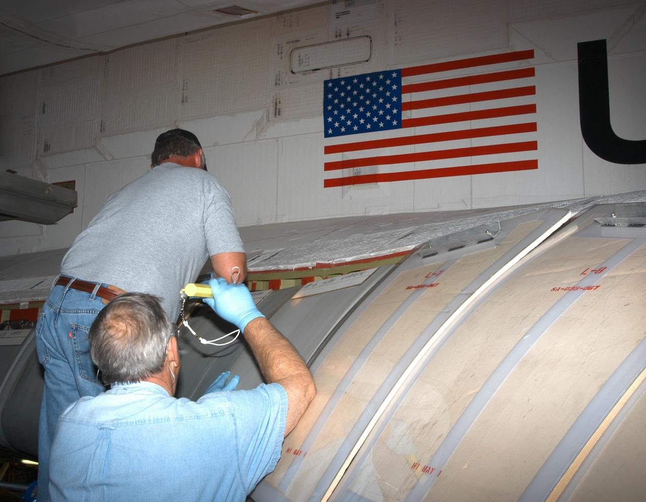 KENNEDY SPACE CENTER, FLA. - In the Orbiter Processing Facility, workers install C-shaped T-seals, which fit between each Reinforced Carbon Carbon panel, on the left-side wing leading edge of the orbiter Atlantis.