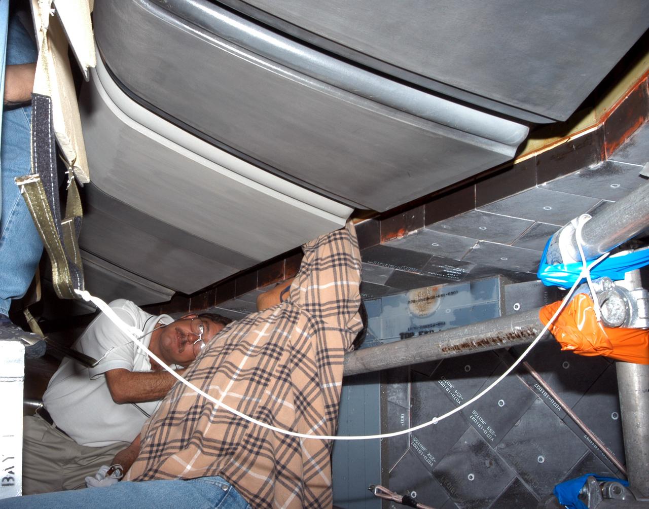 KENNEDY SPACE CENTER, FLA. - - In the Orbiter Processing Facility, workers install C-shaped T-seals, which fit between each Reinforced Carbon Carbon panel, on the left-side wing leading edge of the orbiter Atlantis.