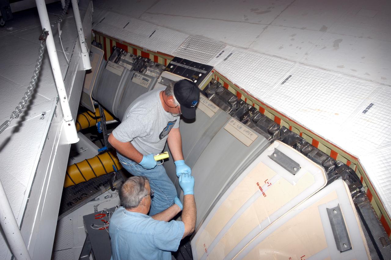 KENNEDY SPACE CENTER, FLA. - In the Orbiter Processing Facility, workers install C-shaped T-seals, which fit between each Reinforced Carbon Carbon panel, on the left-side wing leading edge of the orbiter Atlantis.